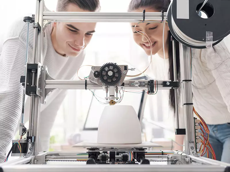 Zwei Studenten beobachten einen 3D-Drucker bei der Arbeit