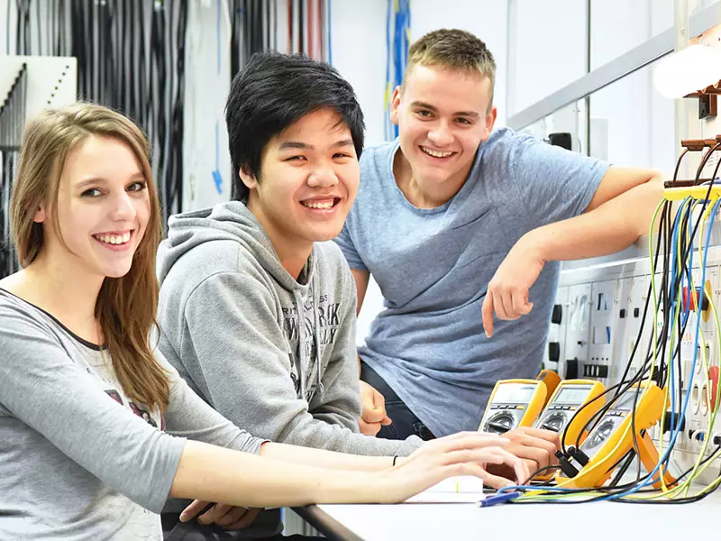 Mehrere Schüler experimentieren mit Hilfe von Messgeräten für Elektrotechnik