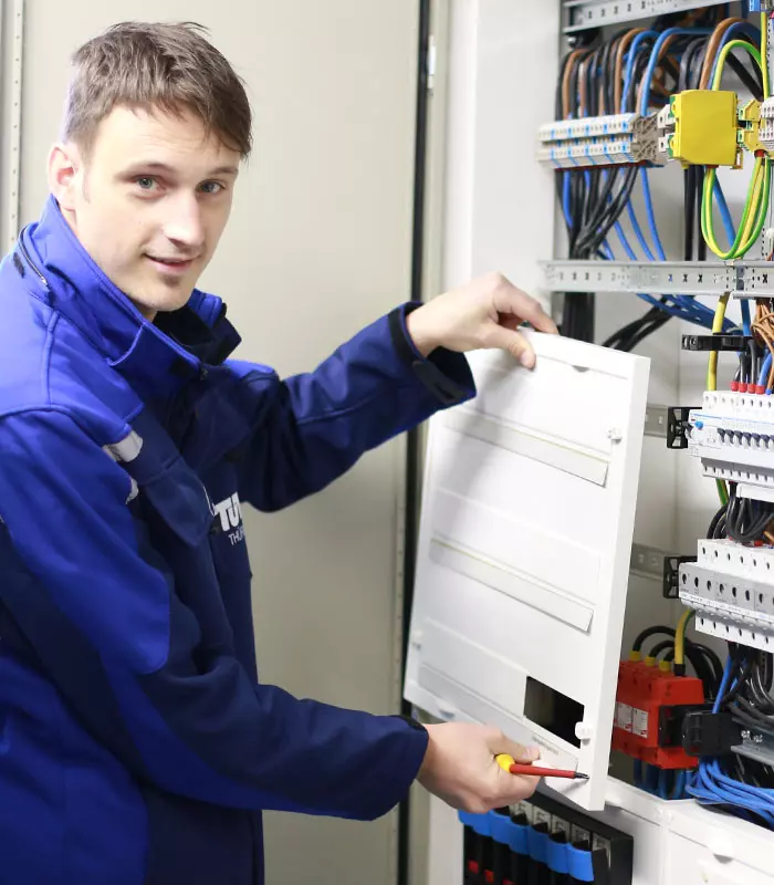 Ein Sachverständiger für Elektrotechnik entfernt die Abdeckung von einem Schaltschrank