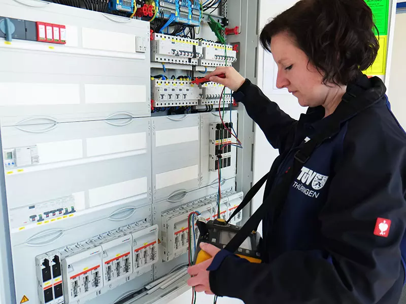 Eine Sachverständige für Elektrotechnik prüft die Technik in einem Schaltschrank