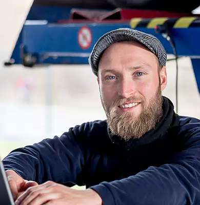 Ein Kfz-Prüfingenieur steht am Laptop in der Auto-Werkstatt
